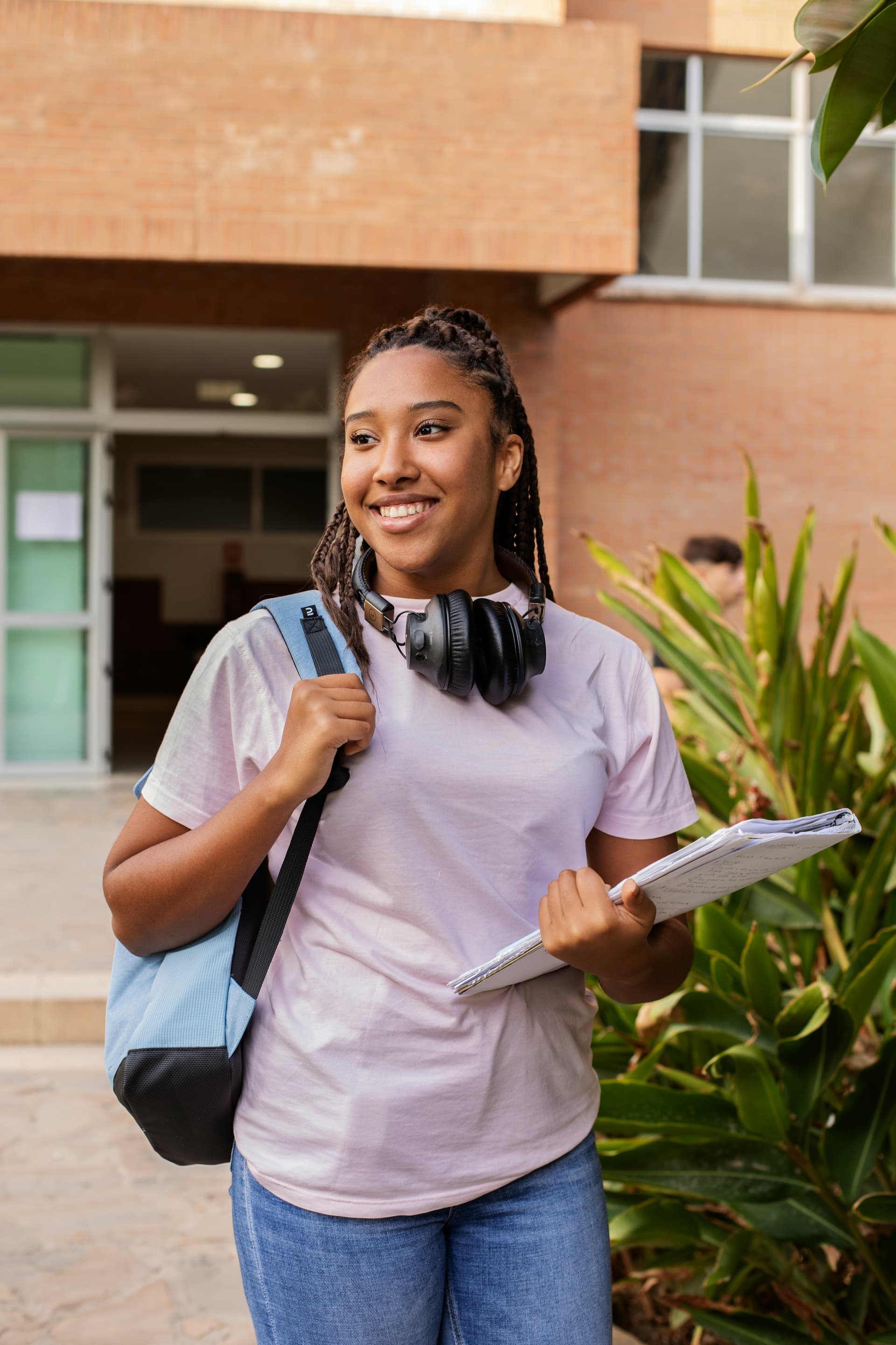 Smiling student with backpack and books walking outside campus