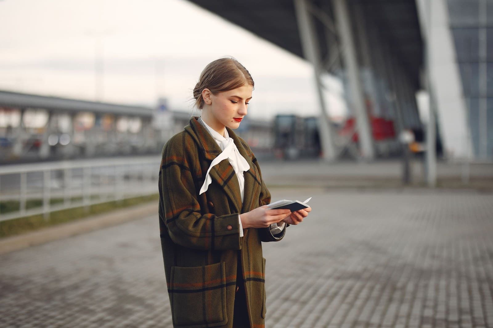 A traveler outside an airport checking her passport and ticket