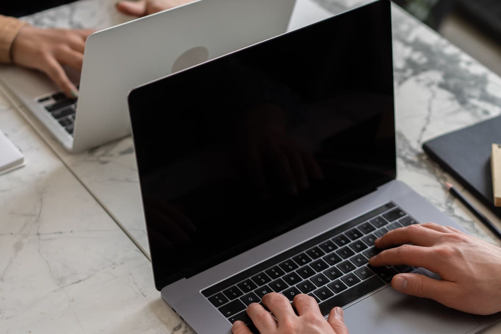 Hands typing on a laptop at a desk