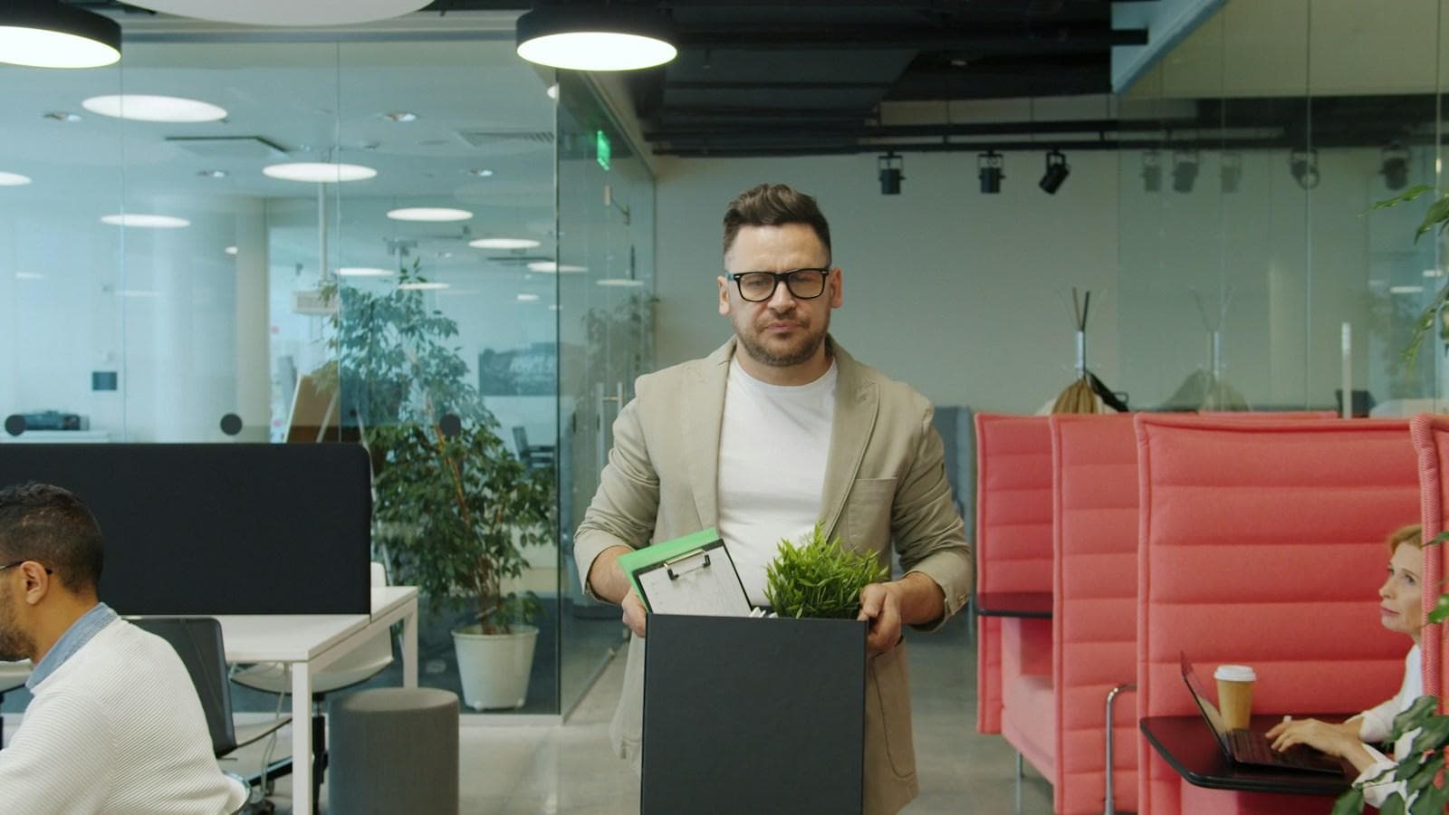 A man carrying a box of personal belongings through an office