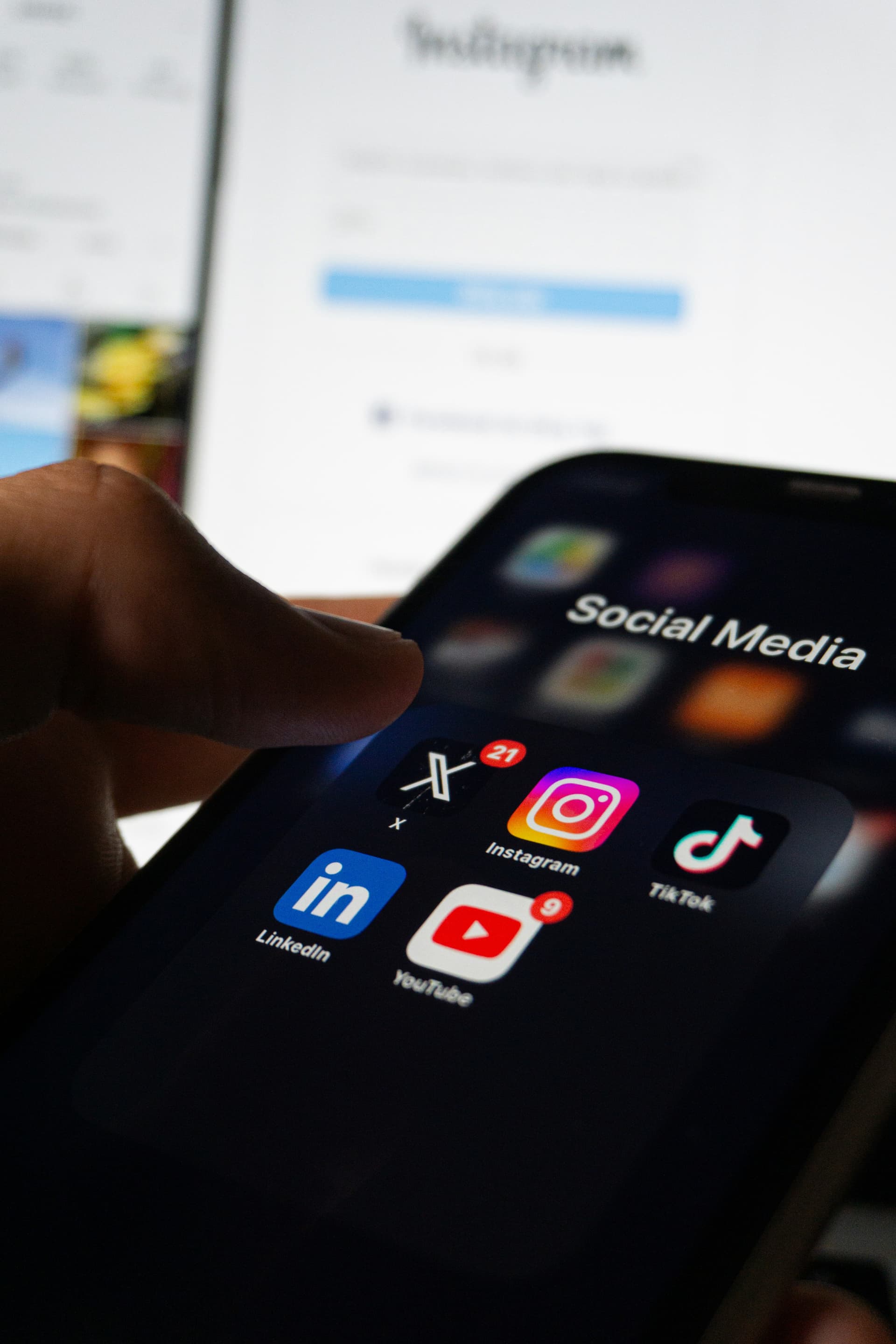 A person holding a smartphone with social media on the screen