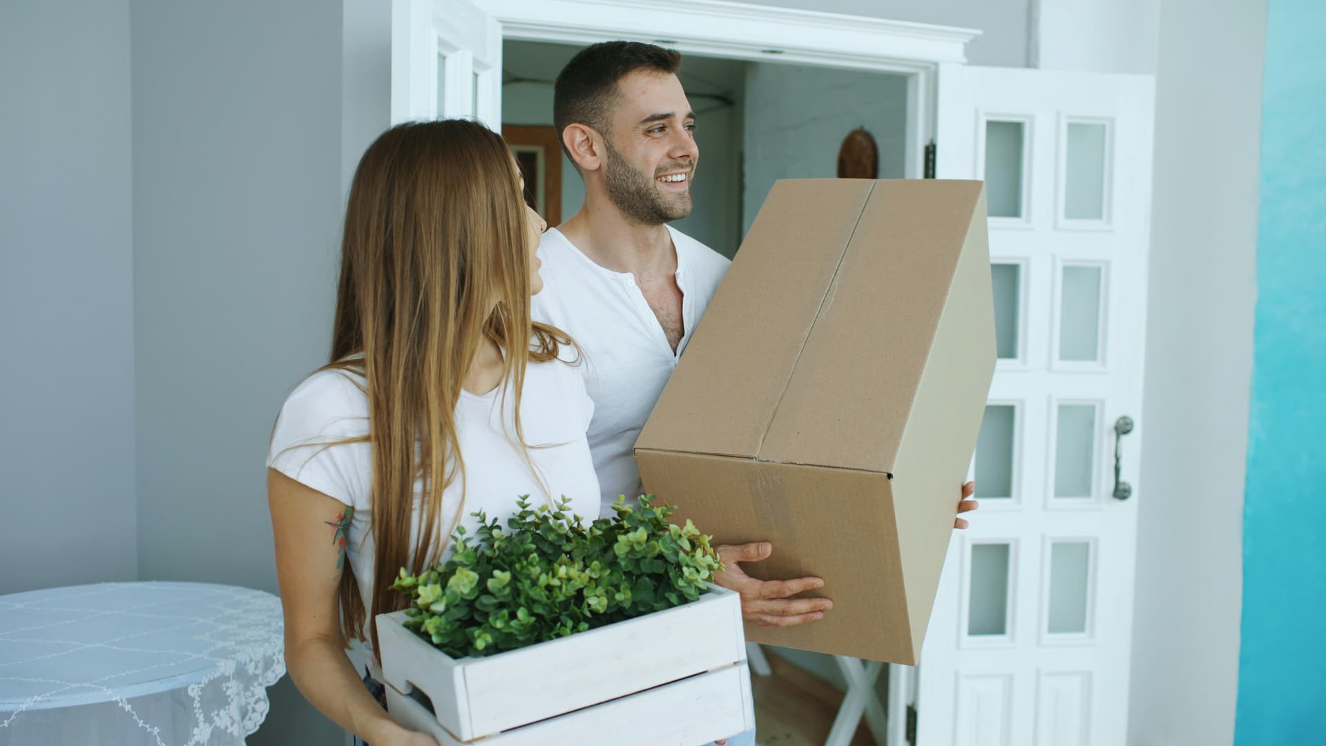 Couple carrying moving boxes into a new home